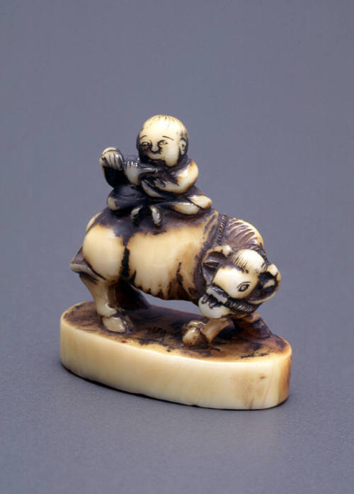 Netsuke modelled as a boy playing a flute astride a water buffalo