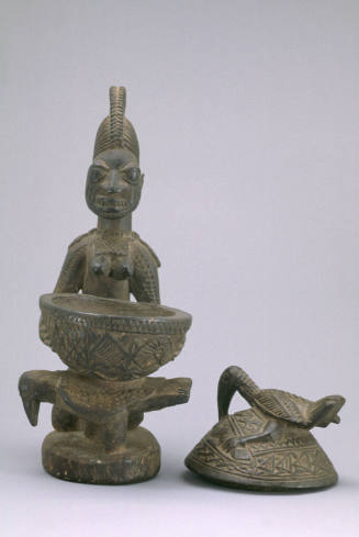 Kneeling woman with covered bowl for kola nuts:  (Olumeye)